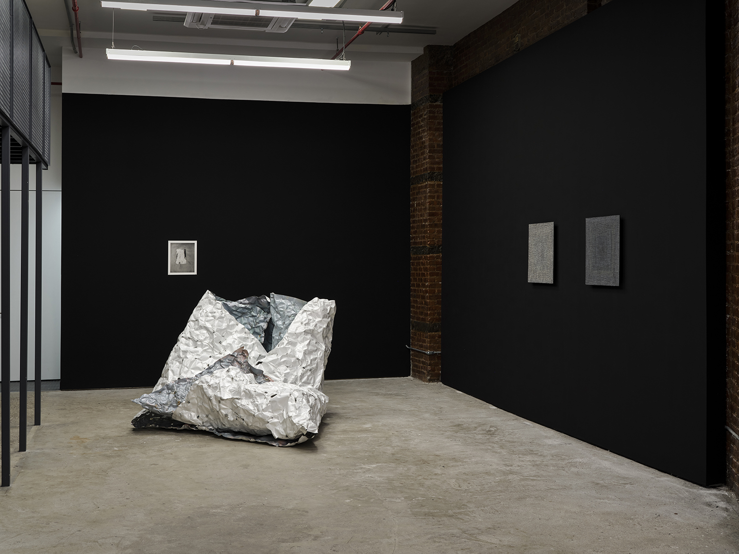 *arms ache avid aeon: Nancy Brooks Brody / Joy Episalla / Zoe Leonard / Carrie Yamaoka: fierce pussy amplified: Chapter Eight,* Curated by Jo-ey Tang, 2025, installation view at Participant Inc, NYC, pictured: Zoe Leonard,* Untitled*, 2016, gelatin silver print, and Joy Episalla, *foldtogram (chromo white/blue, winter 40’ x 50”)*, 2025, light sensitive chromogenic object, and Nancy Brooks Brody,* Glory Hole*, (vibgyor) white on black, 2012, oil on venetian plaster on wood, and Nancy Brooks Brody,* Glory Hole*, (vibgyor) grey on black, 2018, oil on venetian plaster on wood. Photos by Studio Kukla